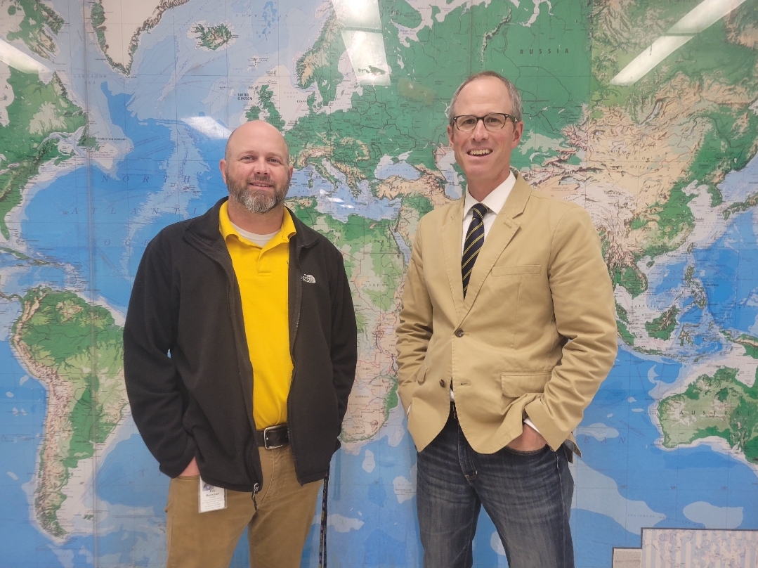 Mr. Hicks and Mr. Beckman strike a pose in front of the iconic green pod map.